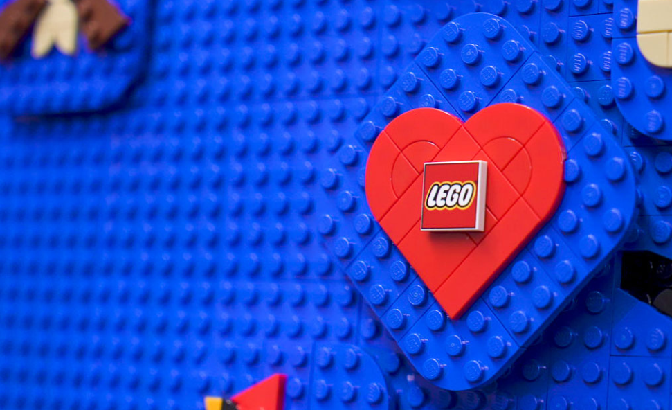 LEGO's logo is shown on LEGO bricks in a red heart on a blue background.